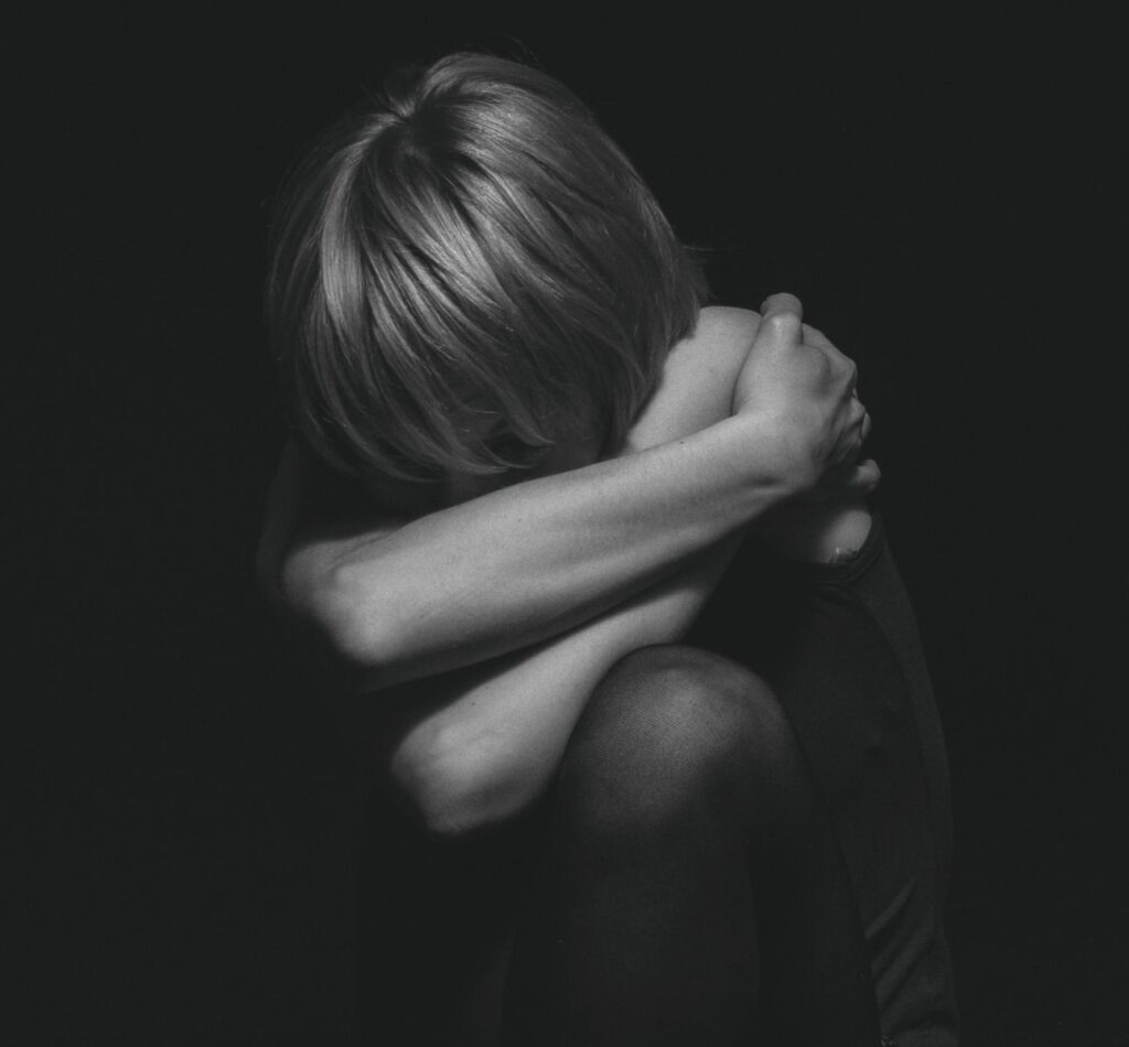 A dramatic black and white portrait capturing deep emotion and solitude in a studio setting.