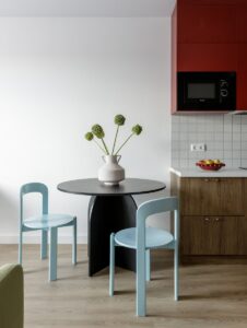 A round black table with two light blue chairs in a modern kitchen
